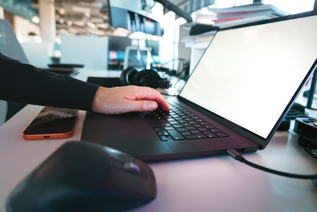 Hand typing on a laptop keyboard in a sleek office environment, showcasing modern technology.
